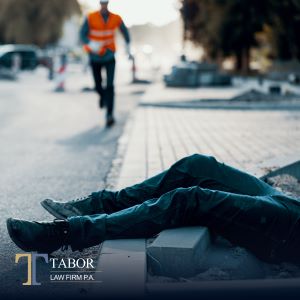A worker rushing to help an injured worker lying on the sidewalk after a fall on a job site
